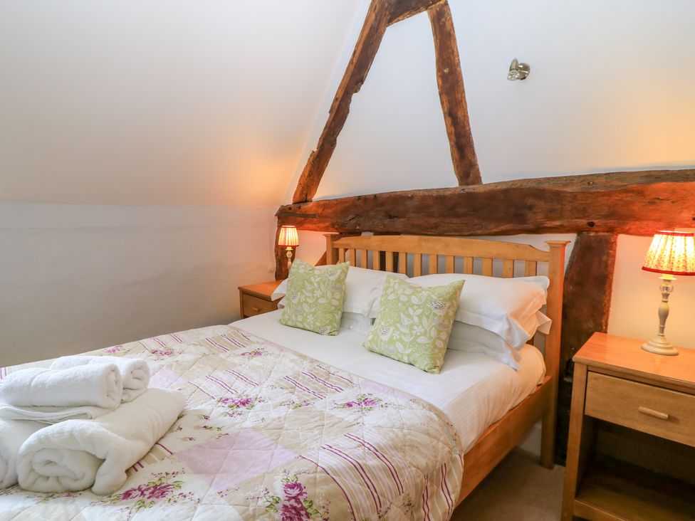 A bedroom with a wooden bed and bedside tables with lamps at April Cottage in Mickleton Gloucestershire