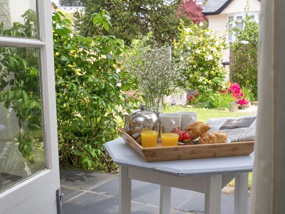 A tray with croissants orange juice and tea on a table by an open door overlooking a garden at 2 Dart in Stoke Gabriel