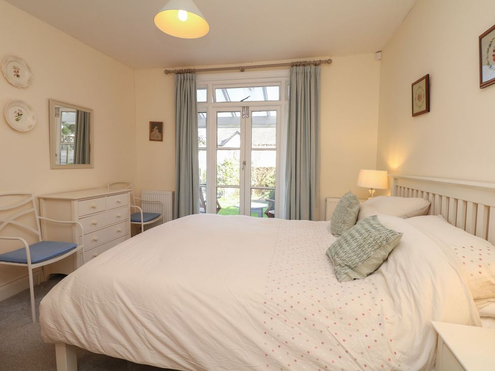 A bedroom with a double bed two chairs a chest of drawers and a window with curtains at 2 Dart in Stoke Gabriel