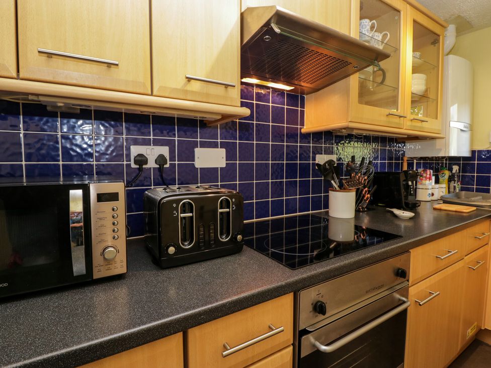 A kitchen countertop with a microwave oven toaster stovetop cooking utensils and cabinets at Buttermere Ambleside