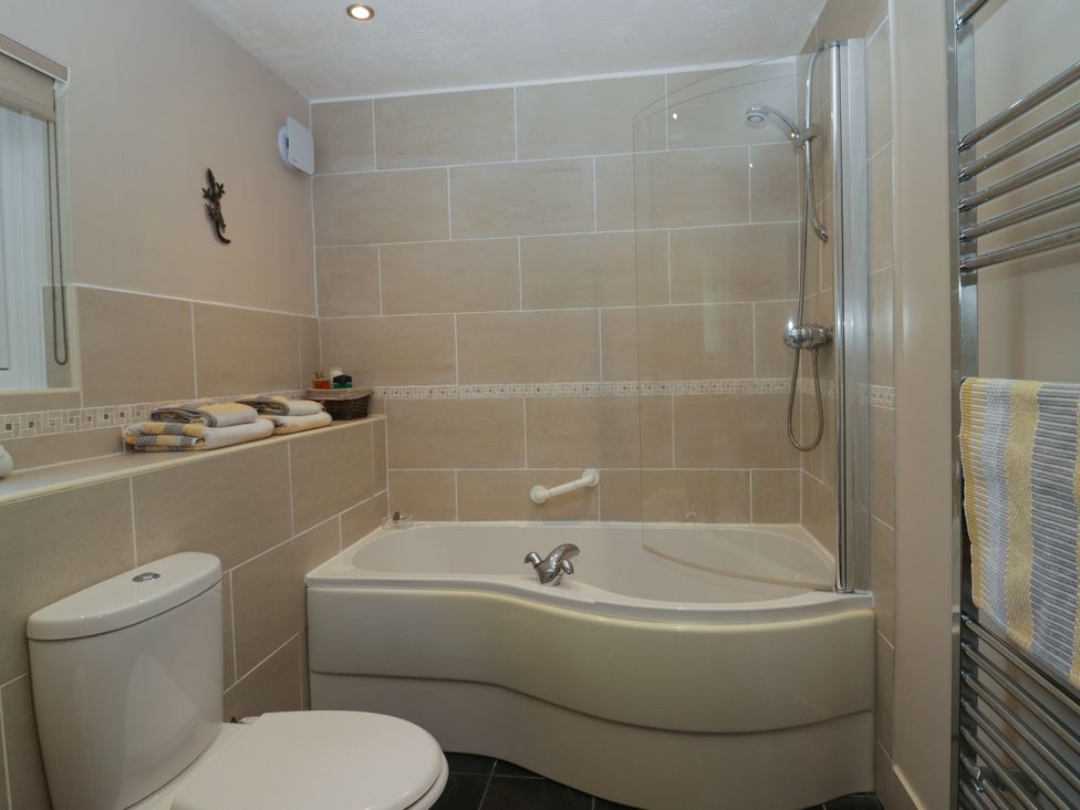 A bathroom with a toilet bathtub with shower and tiled walls at Buttermere in Ambleside