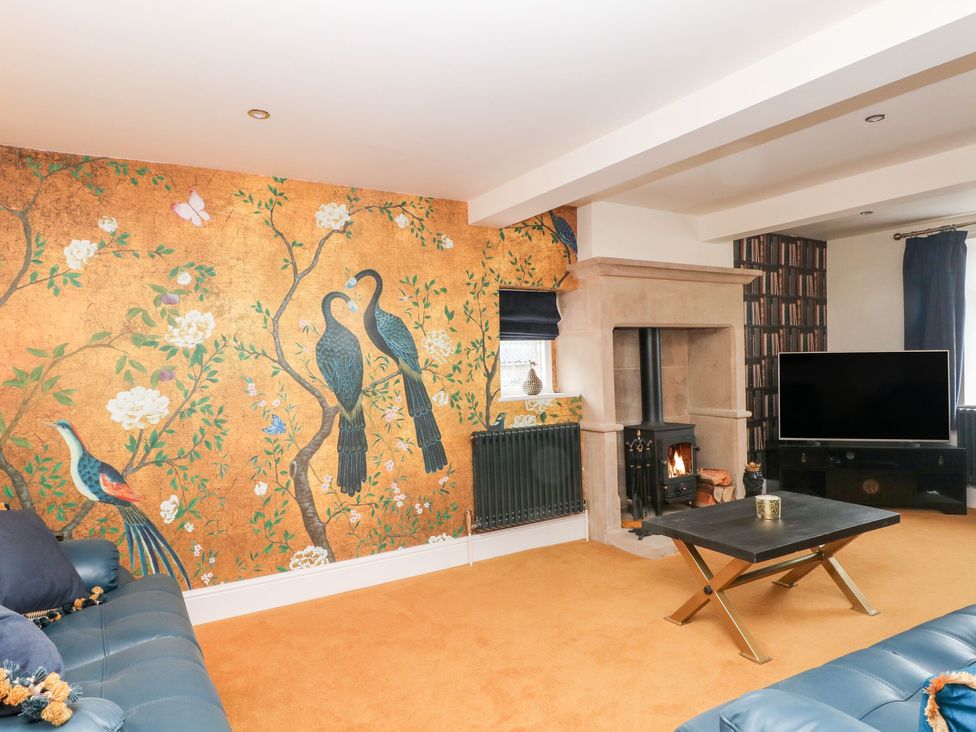 A living room with a bird mural wallpaper a fireplace and a television at HollyDale Bradnop near Leek