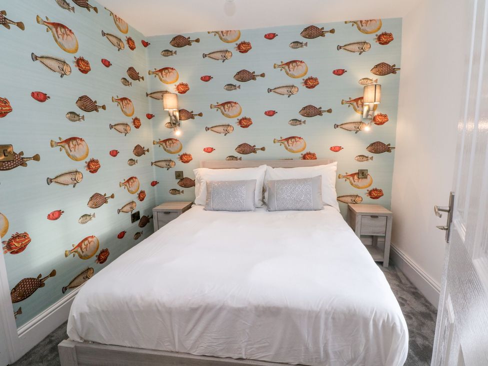 A bedroom with a double bed two bedside tables and fish patterned wallpaper at HollyDale in Bradnop near Leek