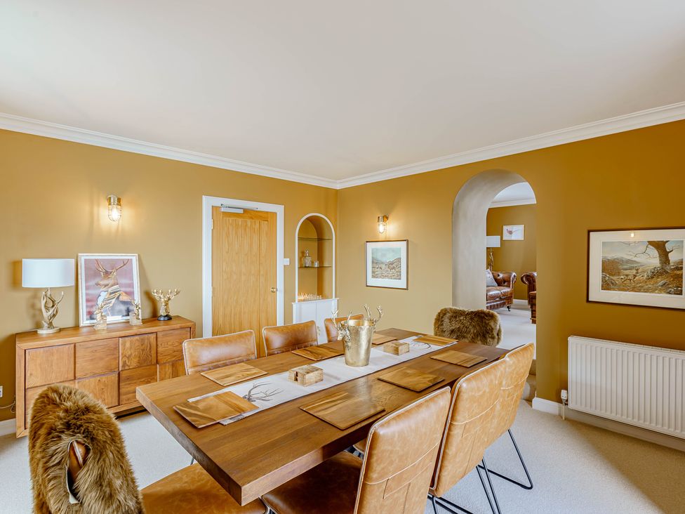 A dining room with a wooden table and leather chairs beside a sideboard and archway at Balcary Tower near Palnackie