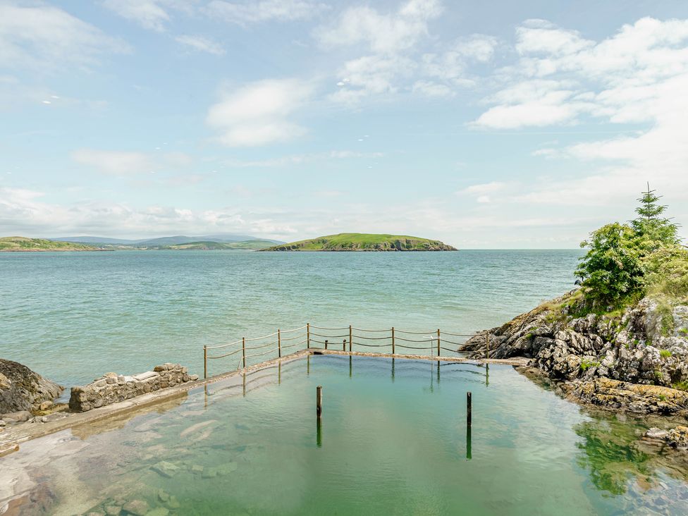 A sea pool with ropes and stone walls overlooking an island and a rocky shoreline at Balcary Tower near Palnackie