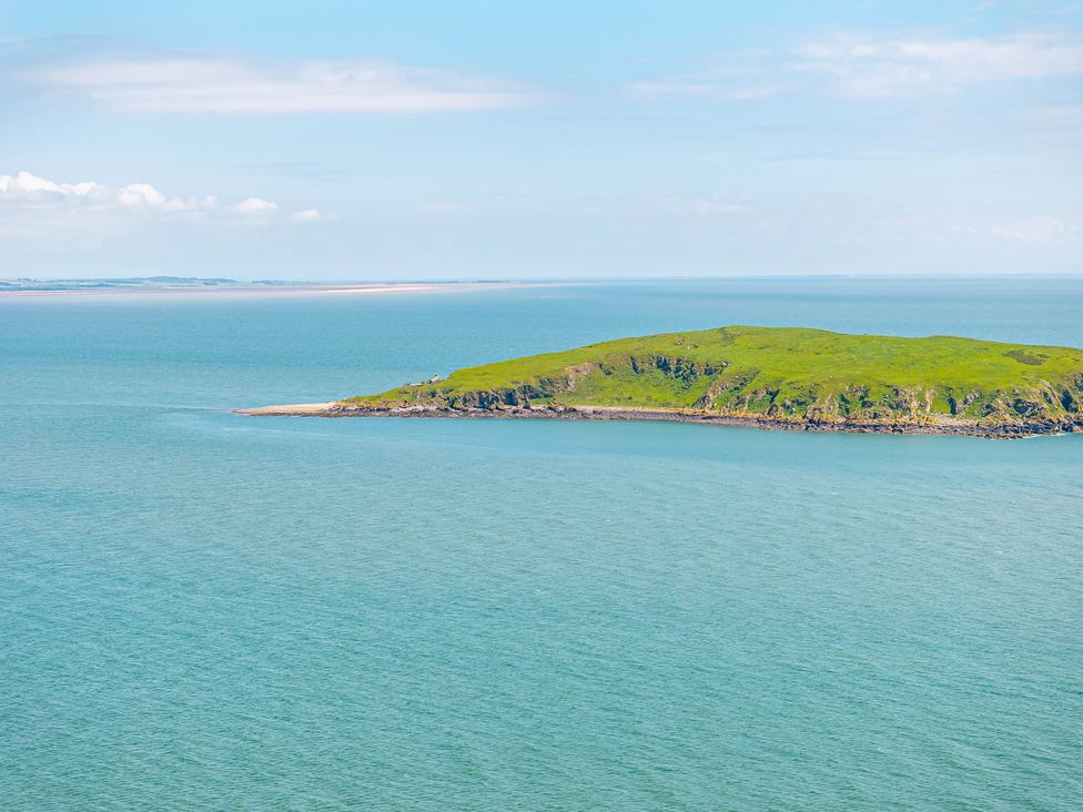 An island with green grass surrounded by a body of water at Balcary Tower near Palnackie