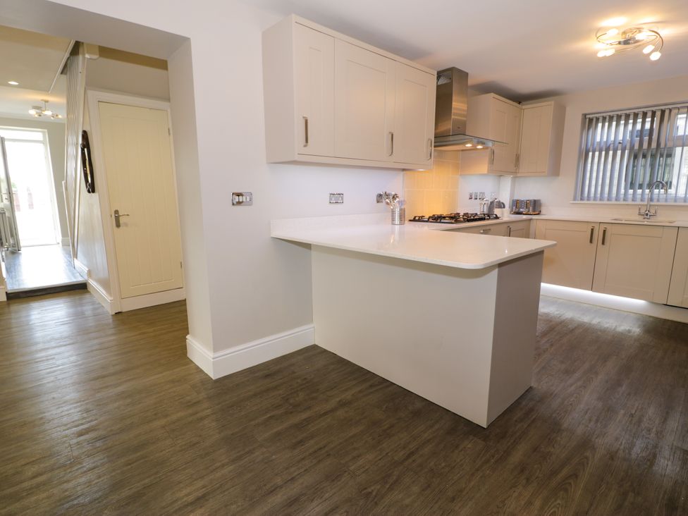 A kitchen with cabinets a countertop stove and a window with blinds at Bwthyn Y Mor in Tal Y Bont