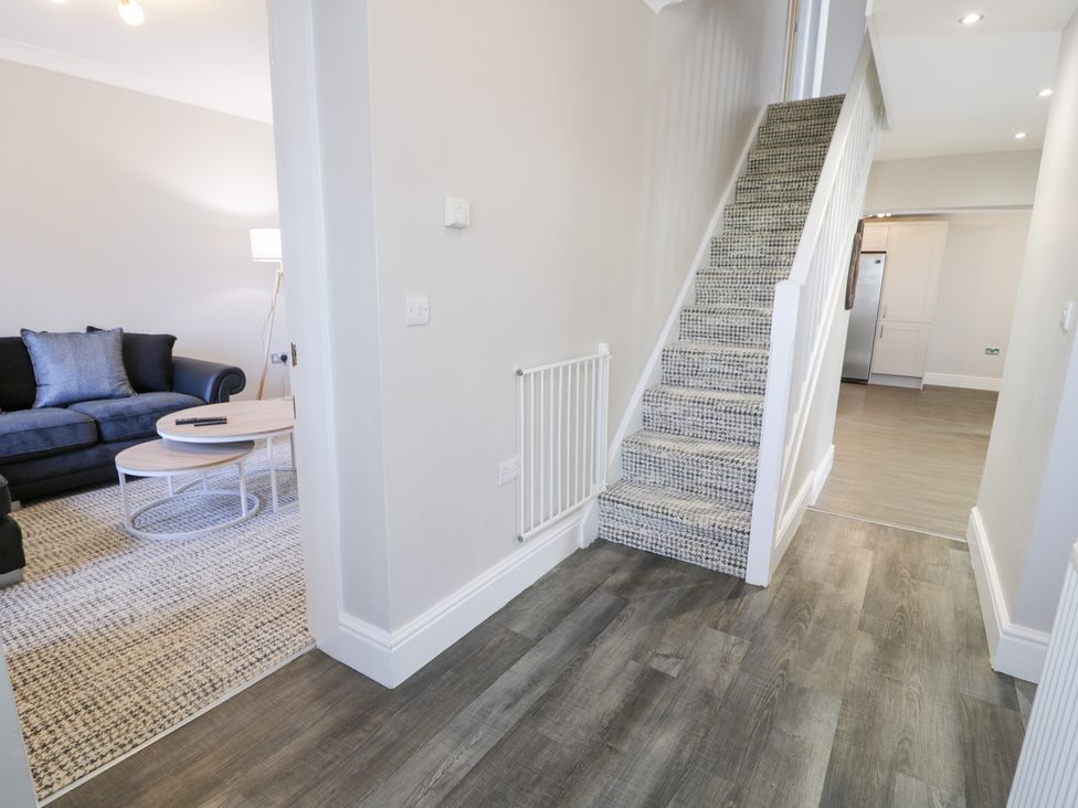 A hallway with carpeted stairs wooden floor and a view of a living room and kitchen at Bwthyn Y Mor in Tal-Y-Bont