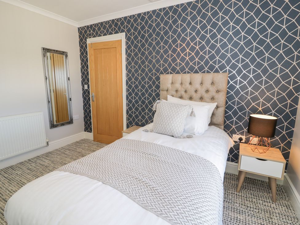 A bedroom with a single bed and a bedside table with a lamp at Bwthyn Y Mor in Tal-Y-Bont