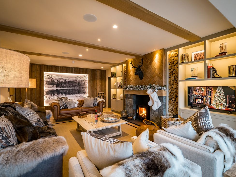 A living room with sofas a wooden coffee table a fireplace and a television at The Ridge in Bowness-On-Windermere