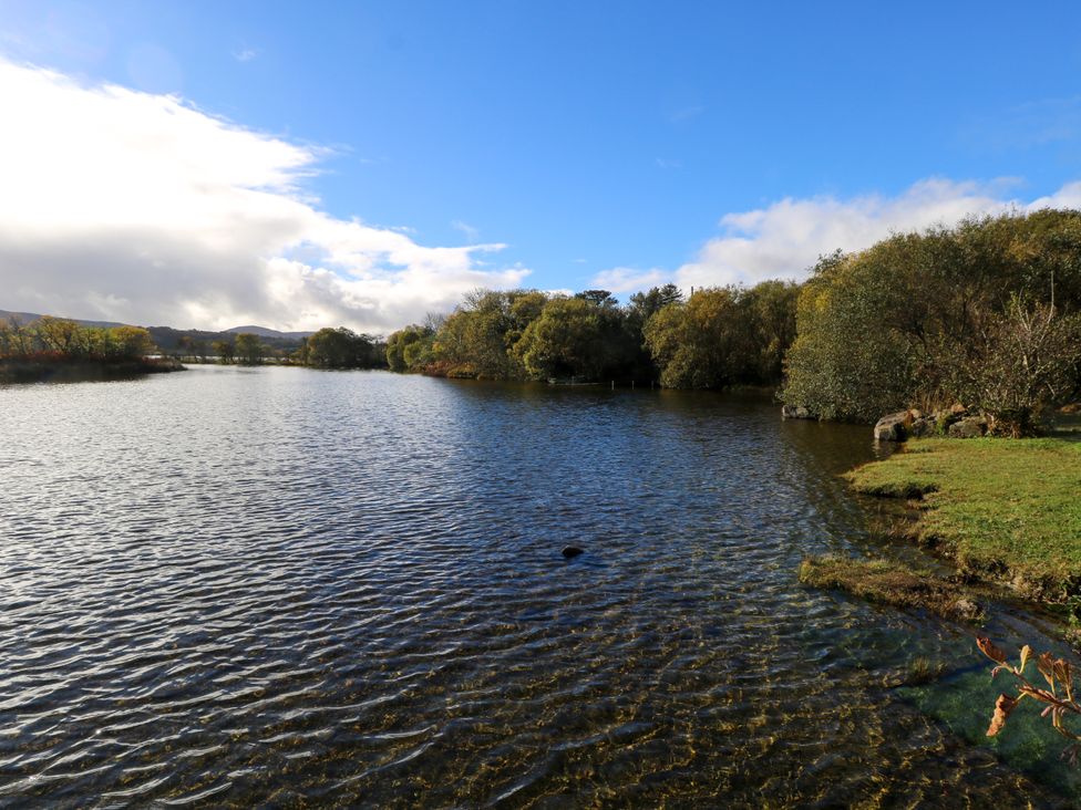 A body of water with trees on the banks under a partly cloudy sky at Robins Roost 2 in Cornamona County Galway