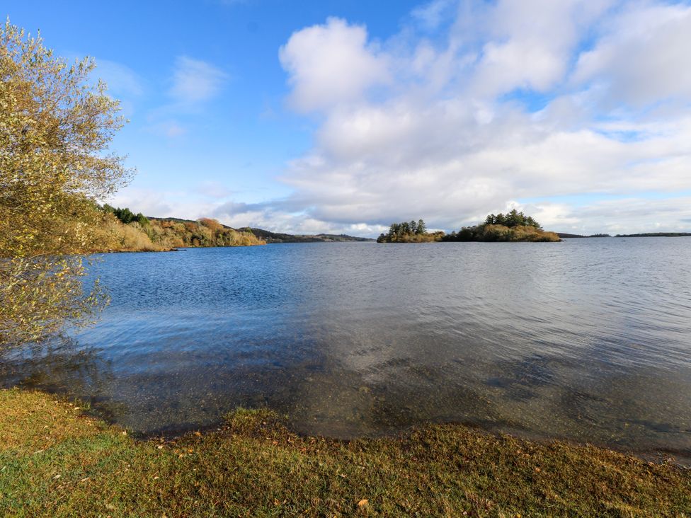 A lake with small islands and trees under a partly cloudy sky at Robin's Roost 2 in Cornamona County Galway