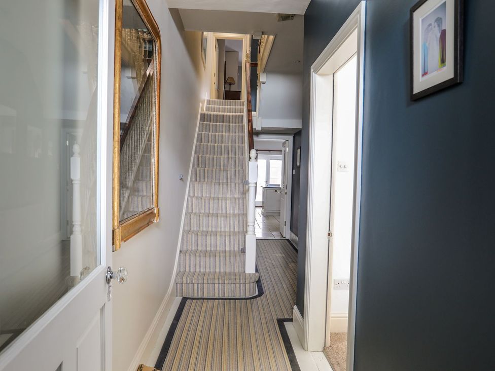 A hallway with stairs and a large mirror on the wall at Morlais in Beaumaris