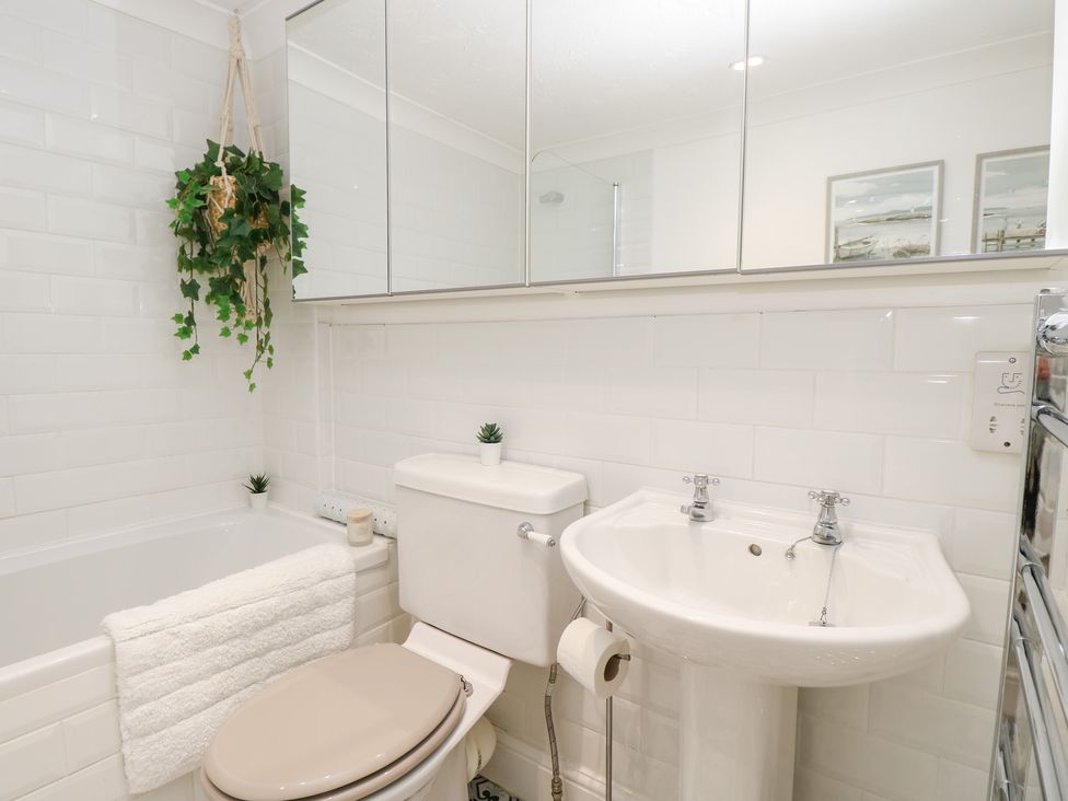 A bathroom with a toilet sink bathtub towel and hanging plant at 3 West Quay Mews in Poole