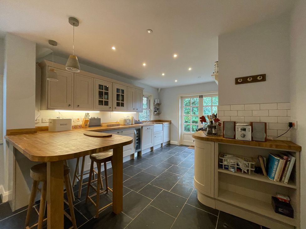 A kitchen with wooden countertops bar stools cabinets and a tiled floor at Bryn Awelon in Harlech