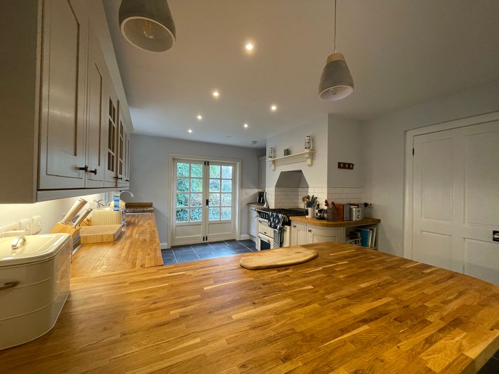 A kitchen with wooden countertops white cabinets and a stove near a door with glass panes at Bryn Awelon in Harlech