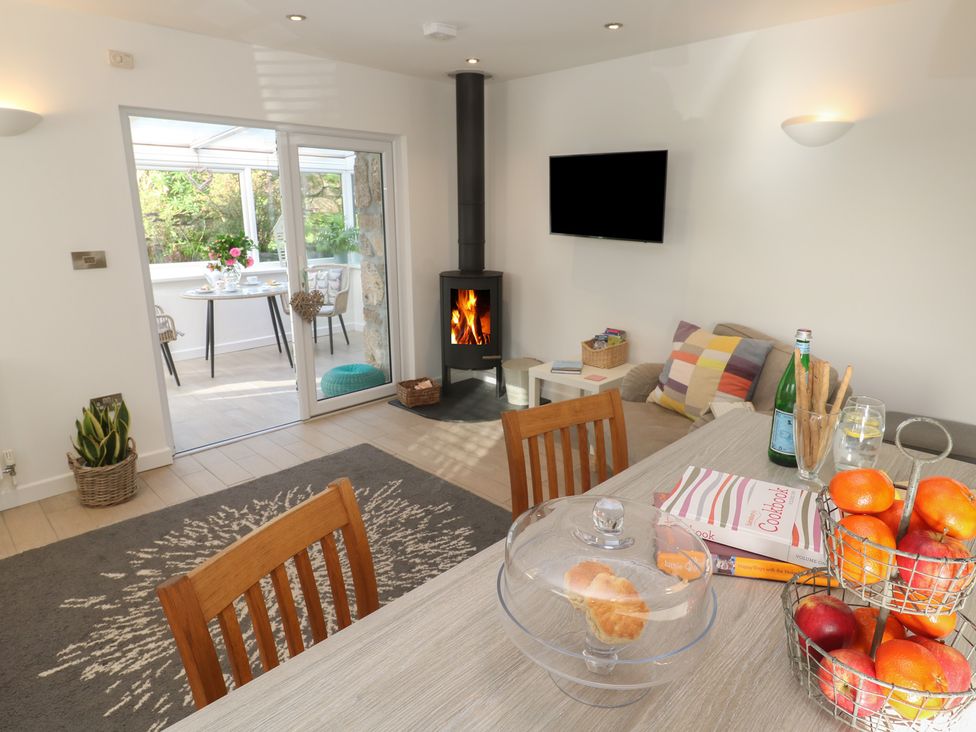 A living area with a wood-burning stove couch and table with fruit at The Duck House in Gulval near Penzance