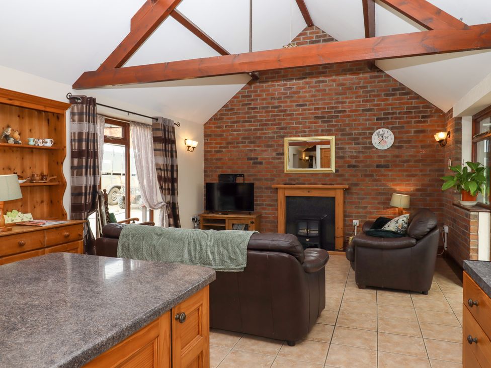 A living room with leather sofas wooden furniture and a brick fireplace at Daisy Cottage in Whitchurch Canonicorum near Charmouth