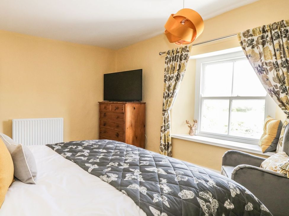 A bedroom with a bed a dresser and a window with floral curtains at St Edmunds House in Crakehall