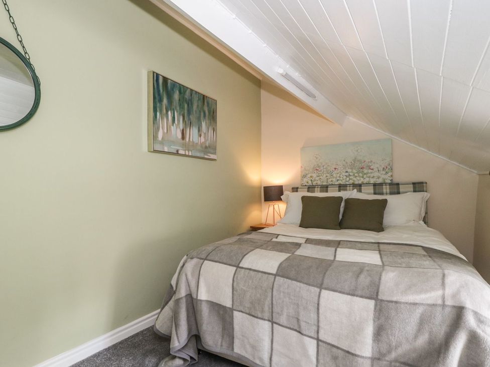 A bedroom with a double bed two pillows a bedside lamp and wall art at St Edmunds House in Crakehall