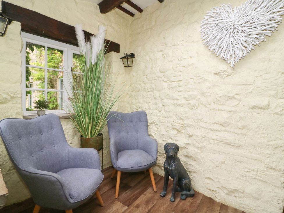 A corner room with two gray chairs a potted tall plant a small window and a black dog statue at St Edmunds House in Crakehall