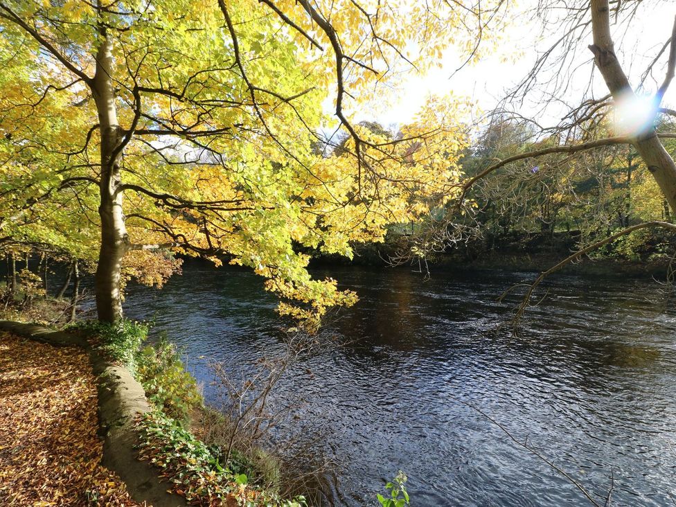 A river with trees along the bank in autumn at St Edmunds House in Crakehall