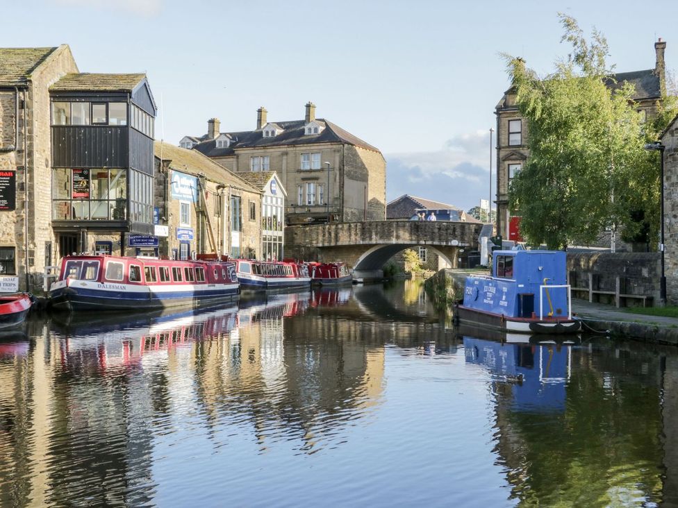 A canal with boats and stone buildings with a bridge in the background at St Edmunds House in Crakehall