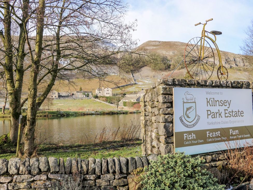 A stone sign for Kilnsey Park Estate near a lake with a vintage bicycle on top and hills in the background at St Edmunds House in Crakehall