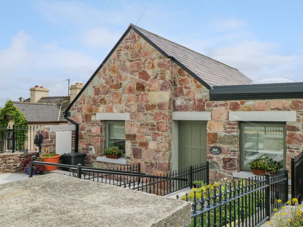 A stone cottage with potted plants and black metal fencing at Neds Cottage in Mulranny County Mayo