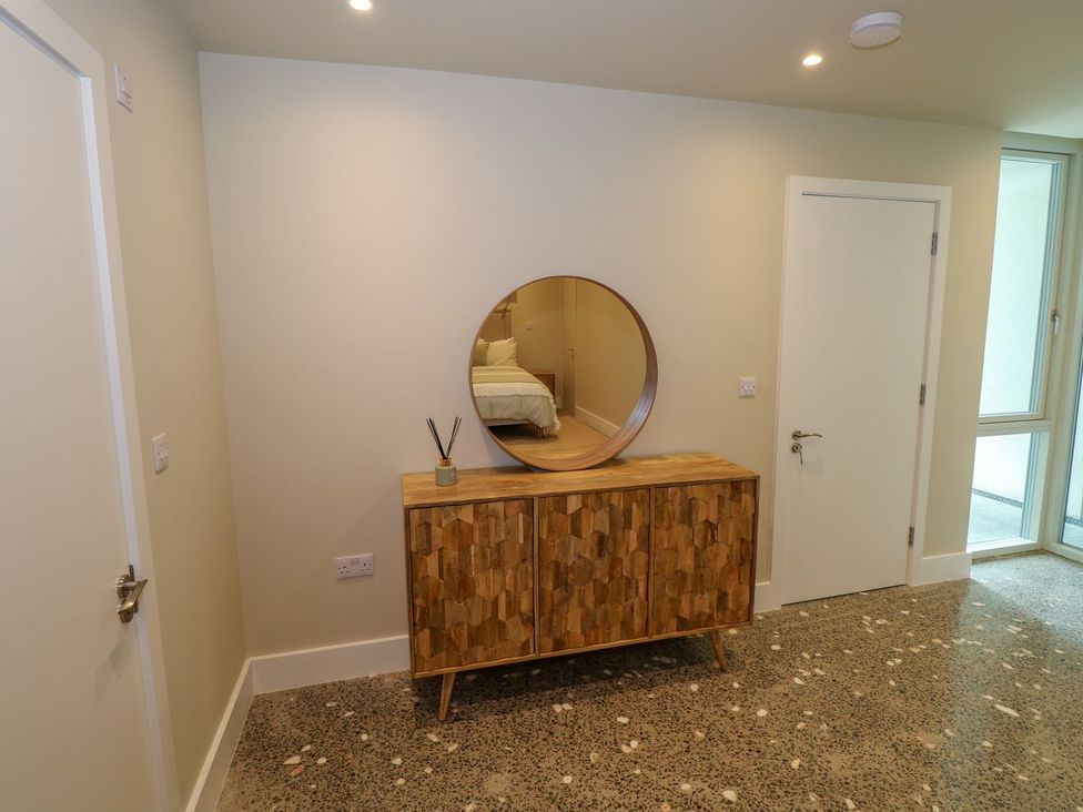 A hallway with a wooden sideboard with a round mirror above it and two white doors in Ned's Cottage Mulranny County Mayo