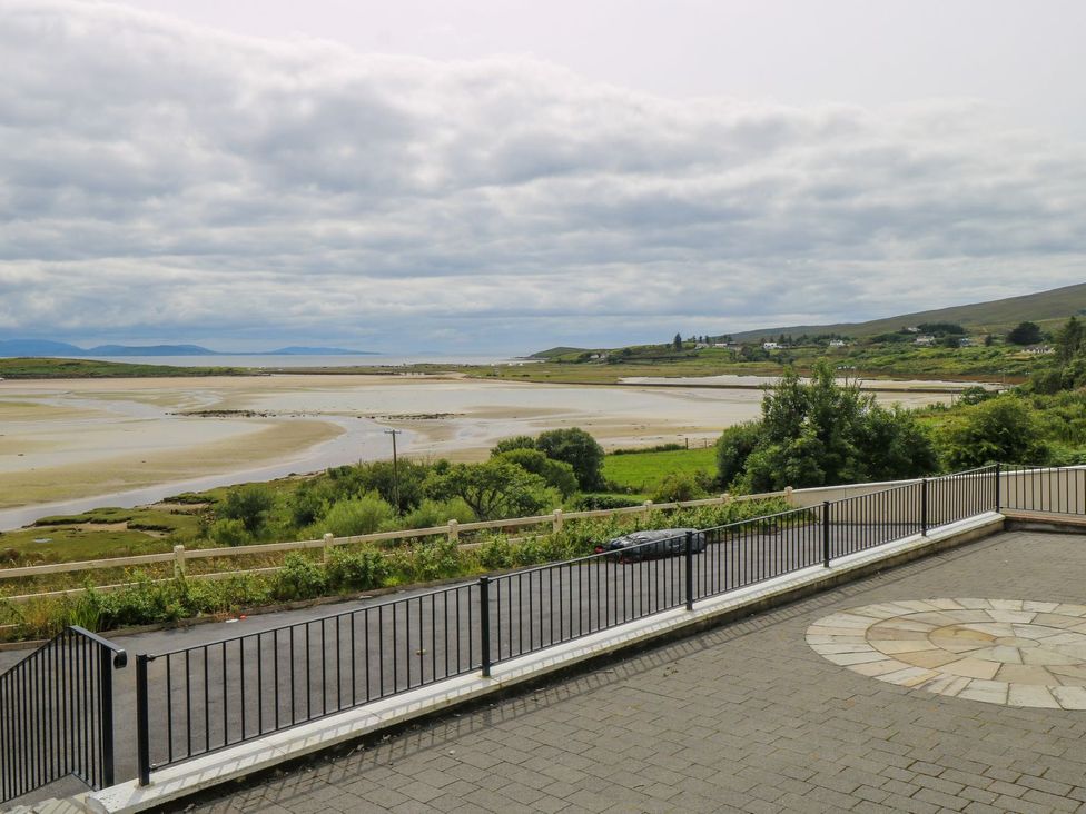 A paved terrace with metal railing overlooking a coastal landscape with sandbanks, greenery, and distant hills at Neds Cottage in Mulranny County Mayo