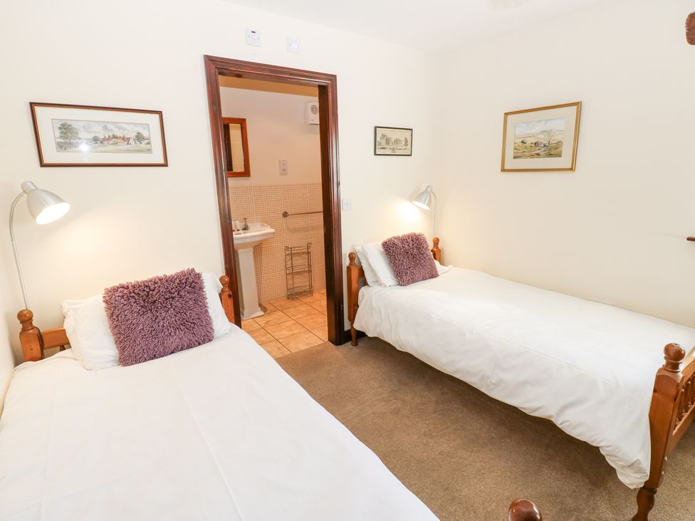 A bedroom with two single beds and a door leading to a bathroom at Pencroft Cottage in Carperby