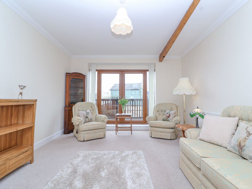 A sitting room with two armchairs a sofa a wooden cabinet a coffee table and large windows at Stapleton Farm Bungalow Damerham near Alderholt