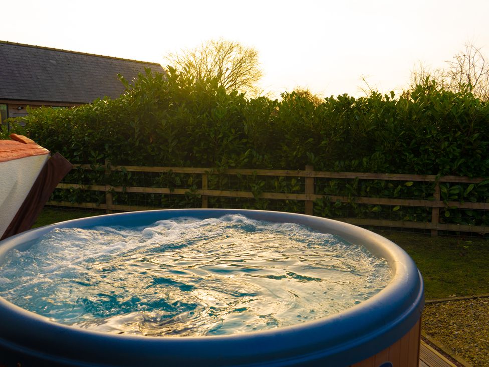 An outdoor hot tub with bubbling water near a wooden fence and greenery at The Green Monkey in North Hykeham