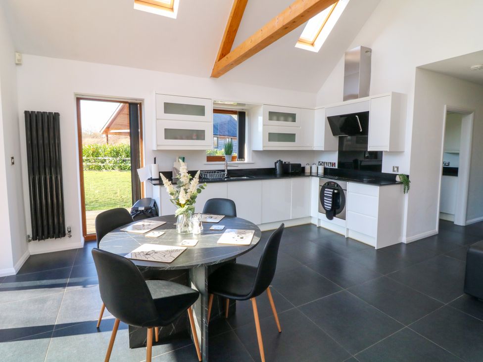 A kitchen with white cabinets a black round dining table with four chairs and skylights at The Green Monkey in North Hykeham