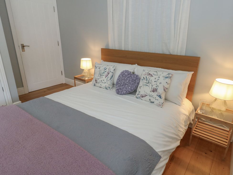 A bedroom with a bed with patterned pillows and lamps on bedside tables at Tothery in Hooke near Beaminster