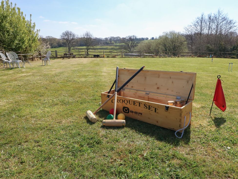 An outdoor grass field with a croquet set including mallets balls and hoops and a red flag at Tothery Hooke near Beaminster