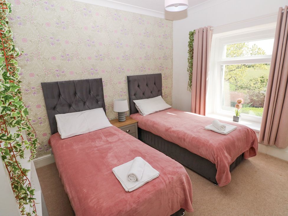 A bedroom with two single beds and pink bedcovers at Burry House in Llanmorlais
