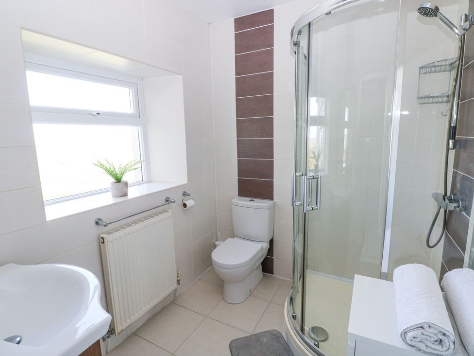 A bathroom with a shower enclosure toilet sink radiator and plant on the windowsill at Burry House in Llanmorlais