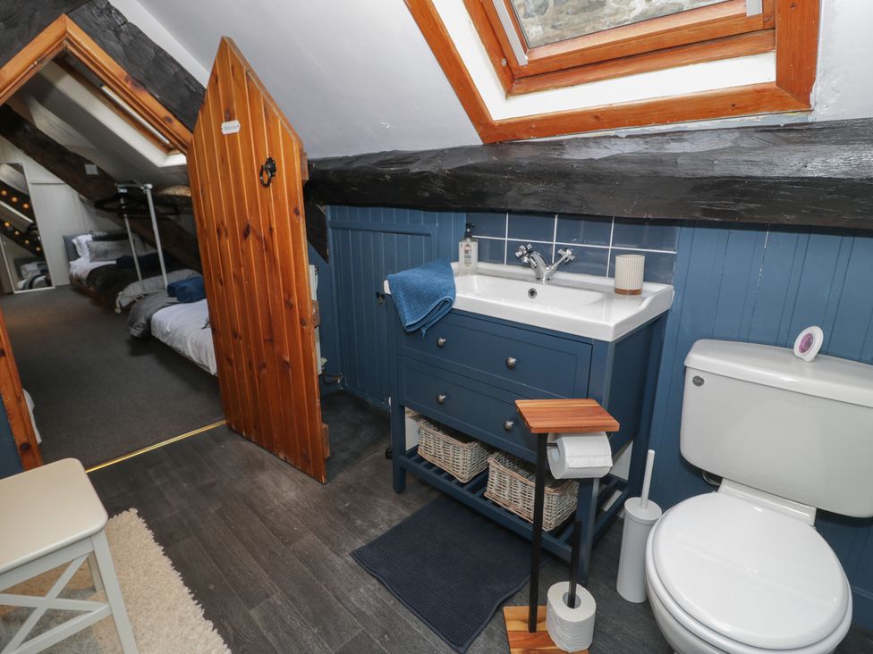 A bathroom with a toilet sink and wooden door leading to a bedroom at Penygresiau in Barmouth