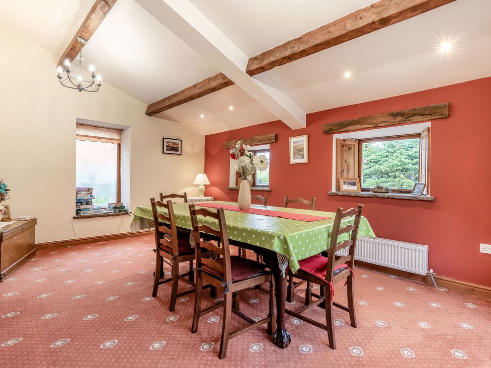 A dining room with a green polka dot tablecloth on a table and wooden chairs at Brant View in Cautley near Sedbergh