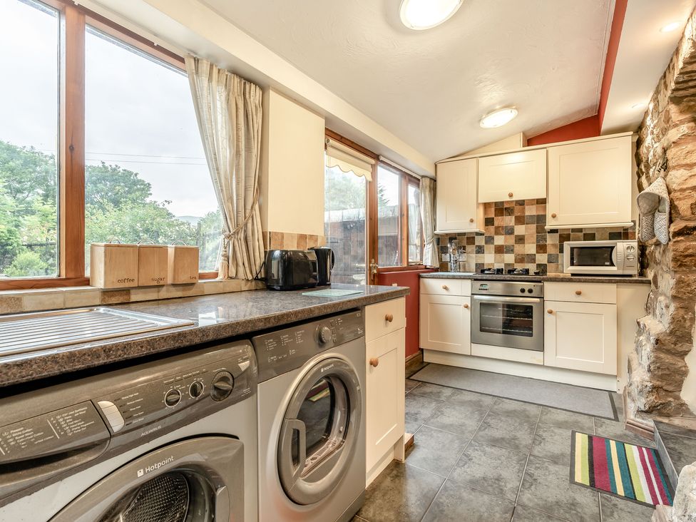 A kitchen with washing machine, dryer, oven, microwave and windows at Brant View in Cautley near Sedbergh
