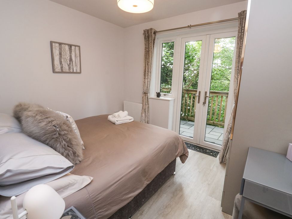 A bedroom with a bed and pillows near glass doors leading to a balcony with trees outside at Treetops in Southerton