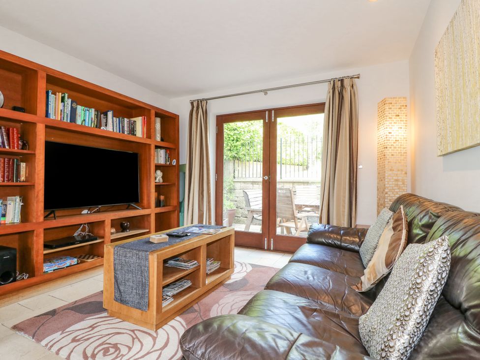 A living room with a leather sofa pillows wooden bookshelf television and coffee table at Torestyn in Darley Dale