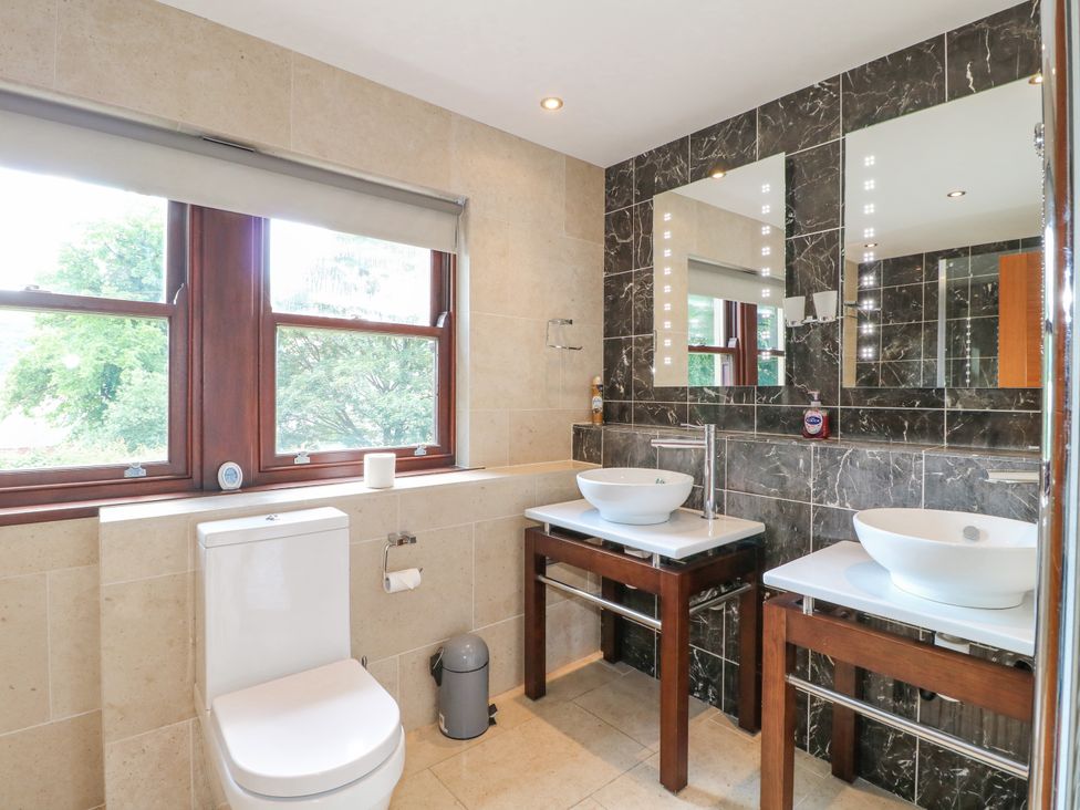 A bathroom with a toilet and two sinks with mirrors above at Torestyn in Darley Dale