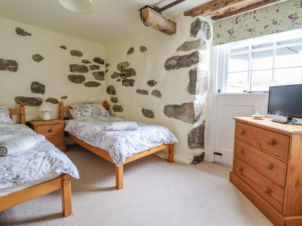 A bedroom with two single beds a wooden chest of drawers and a window at Ysgybor Yd in Chwilog near Criccieth