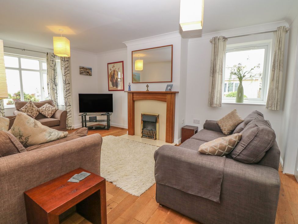 A living room with sofas a fireplace a television and windows at 5 Cae Derwydd in Cemaes Bay