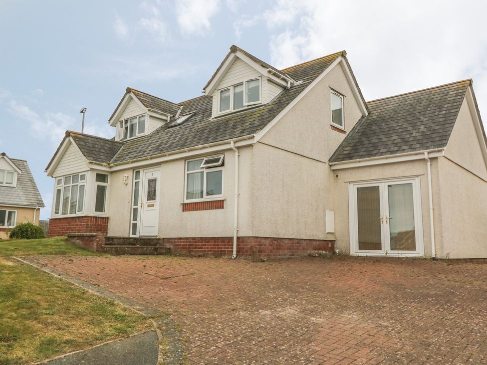A detached house with a brick driveway and a grass lawn at 5 Cae Derwydd in Cemaes Bay