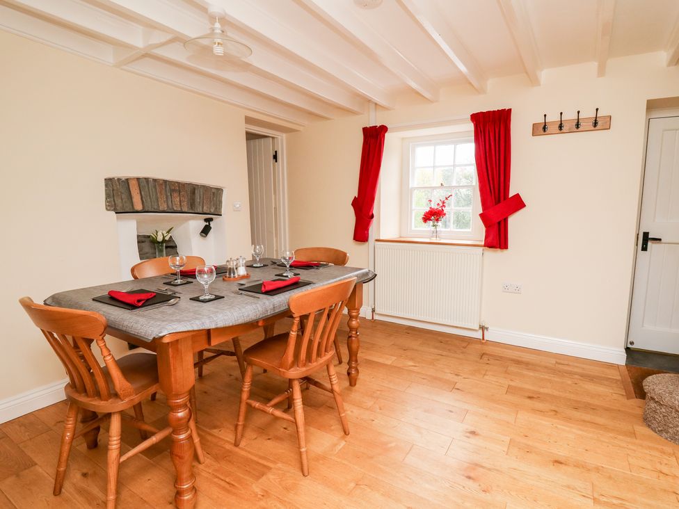 A dining room with a wooden table and chairs set with red napkins and glassware at Penlon in Capel Bangor near Aberystwyth