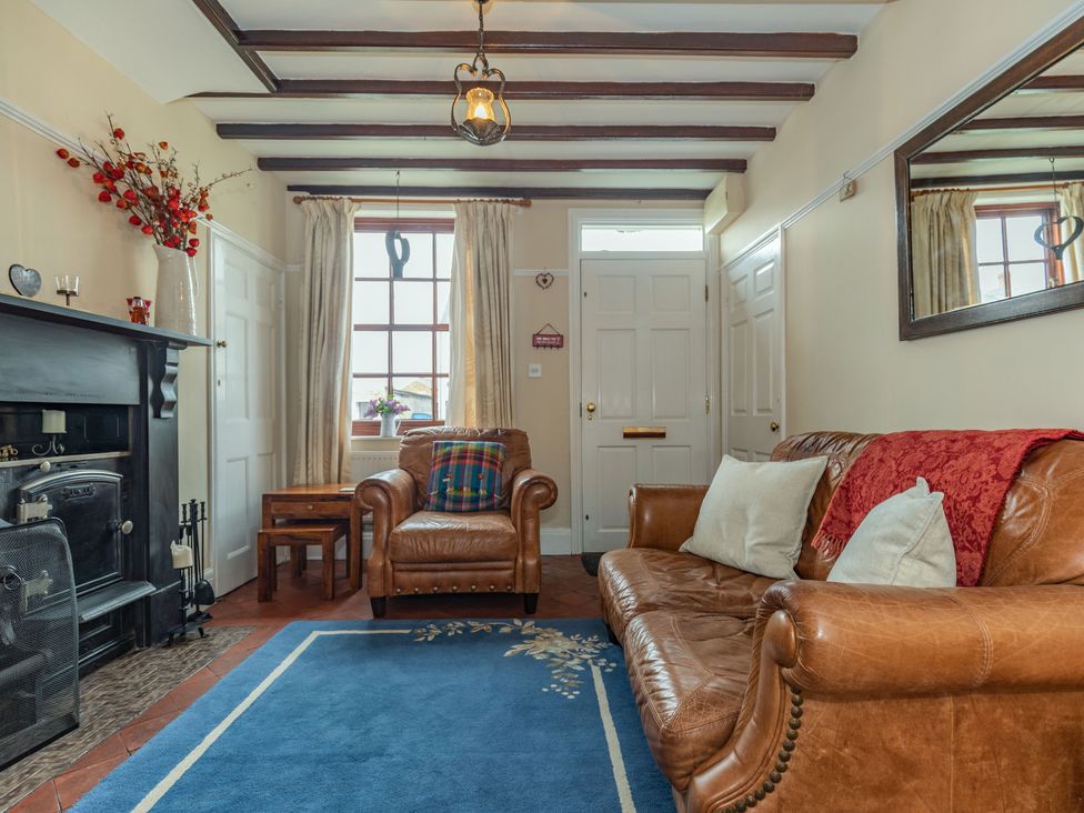 A living room with leather sofas and a fireplace at Chapel Cottage in Stillington near Easingwold and York